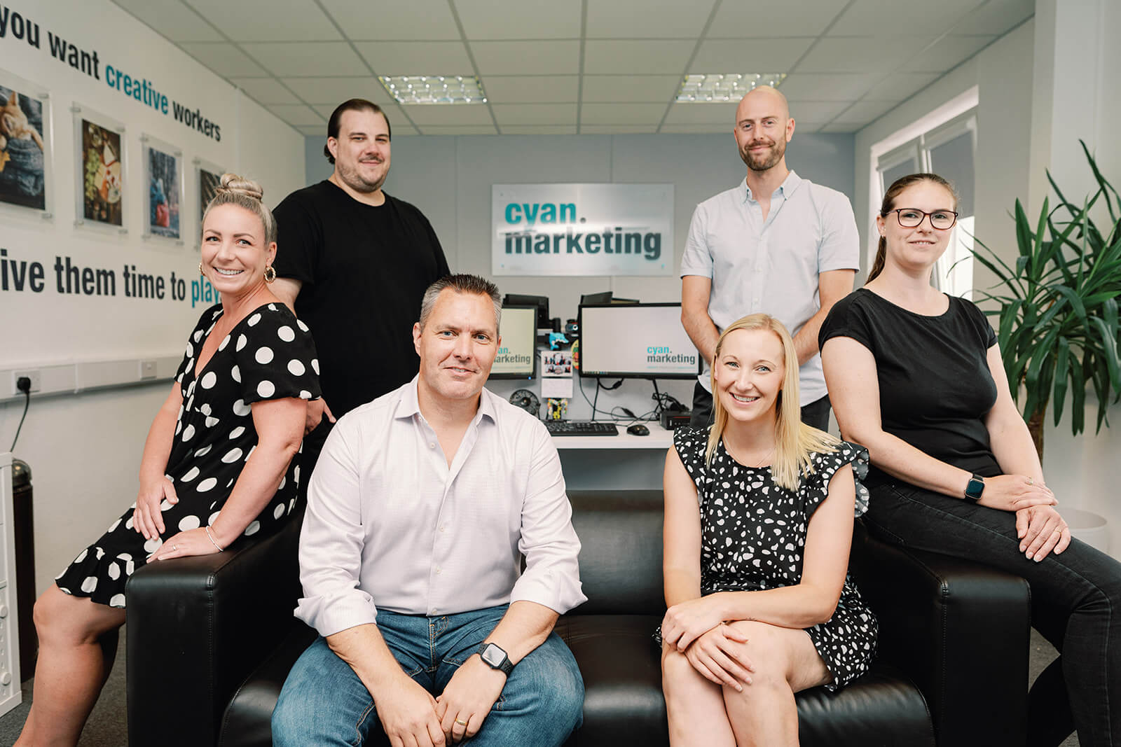 Cyan team posing around a sofa in their office